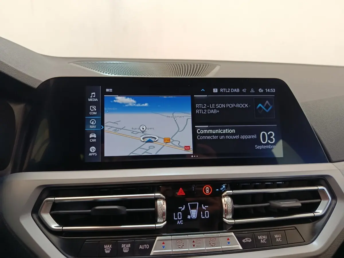 Vue rapprochée de l’écran tactile central et des commandes de climatisation d’une BMW Série 3 320e hybride blanche, intérieur moderne.