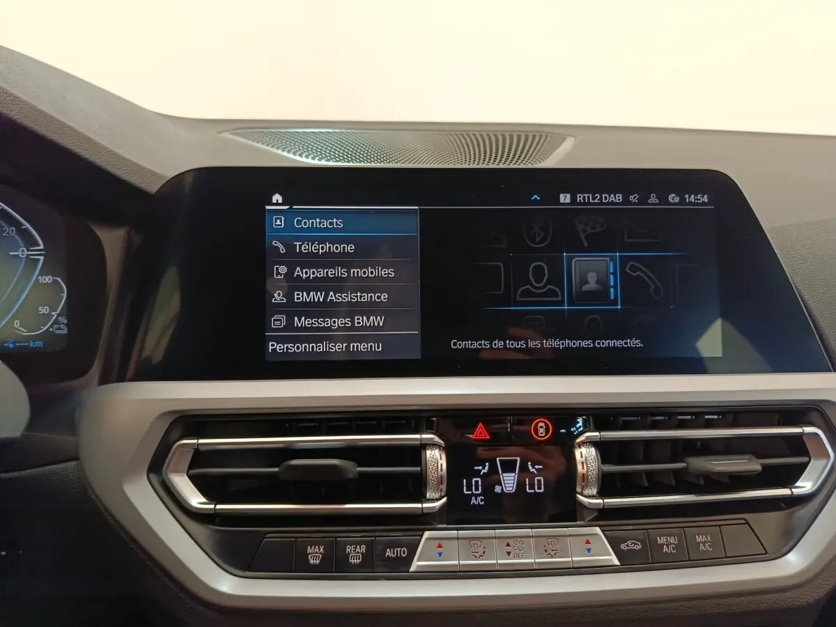 Vue rapprochée de l’écran tactile central et de la console de climatisation d’une BMW Série 3 blanche, intérieur moderne.