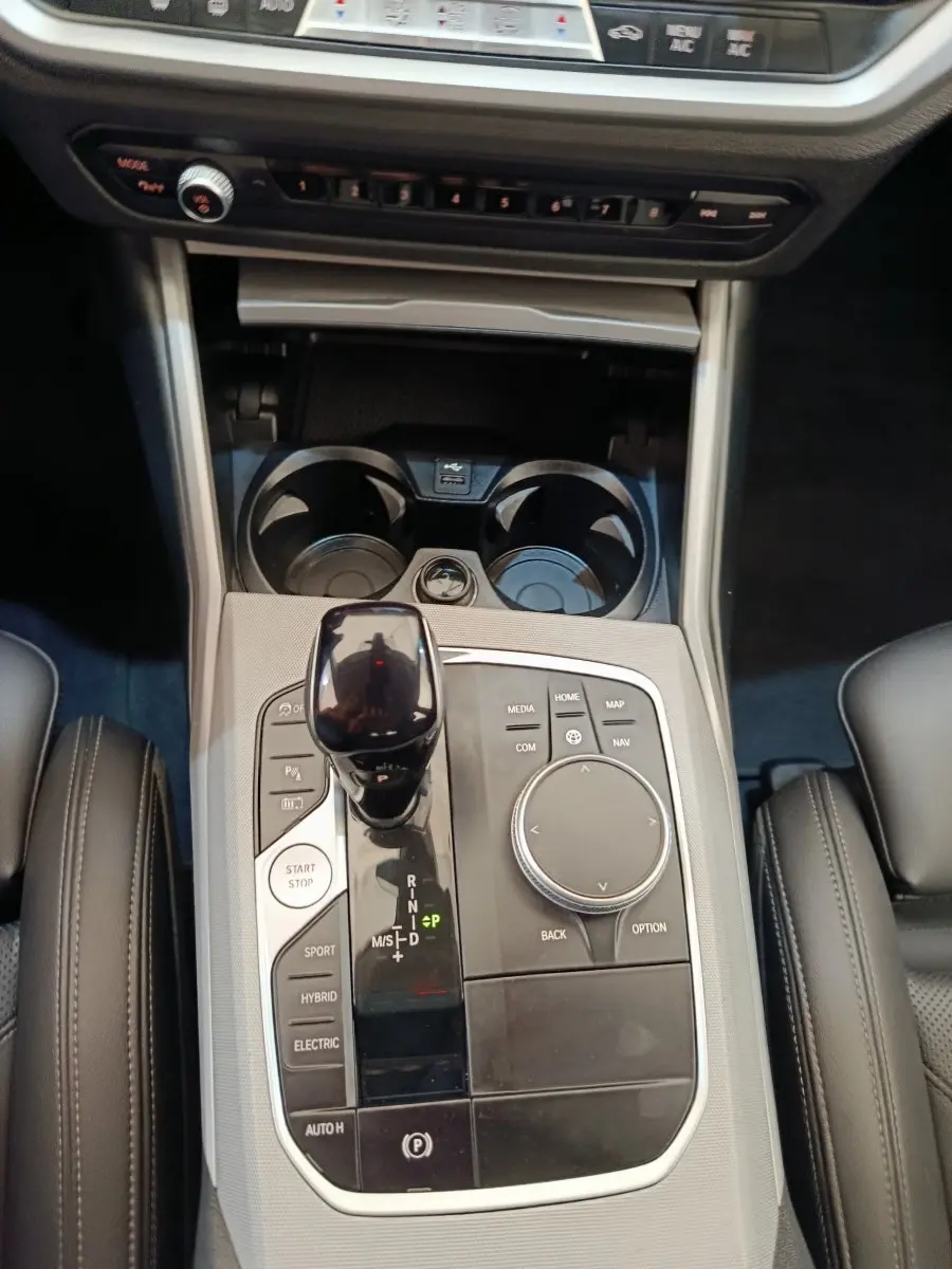 Vue rapprochée de la console centrale noire et argentée de la BMW Série 3 320e hybride avec levier de vitesse et boutons multifonctions.