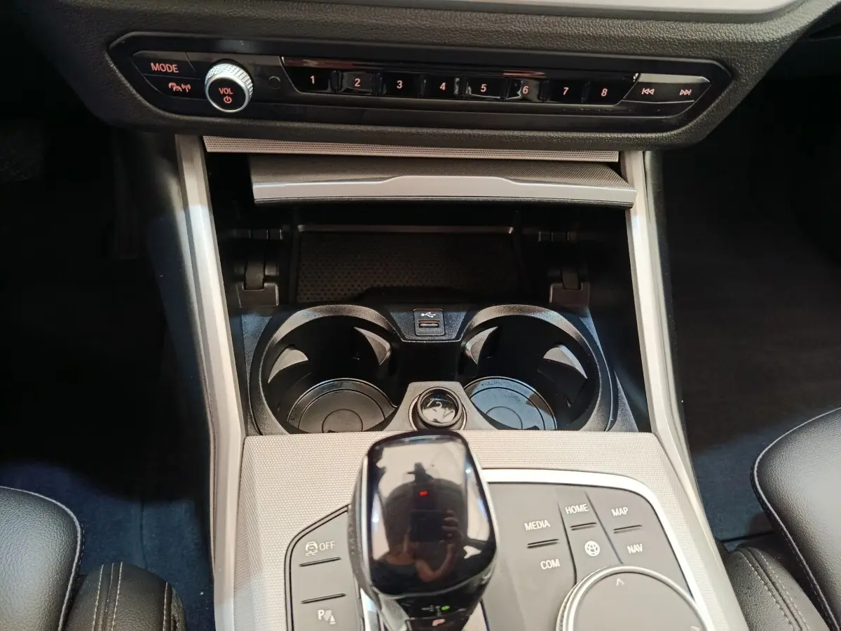 Vue rapprochée de la console centrale noire et argentée de la BMW Série 3 320e hybride avec sélecteur de vitesse et porte-gobelets.
