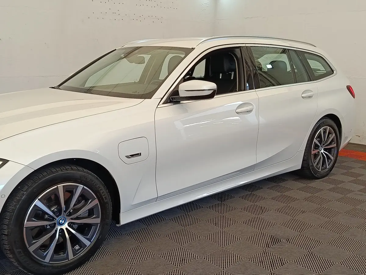 BMW Série 3 320e hybride blanche vue de profil côté gauche, avec jantes alliage et prise de recharge visible.