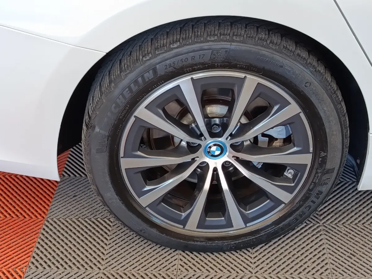 Gros plan sur la roue avant droite blanche d’une BMW Série 3 320e hybride avec jante alliage gris foncé.
