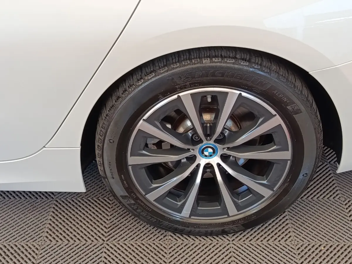 Gros plan sur la roue arrière droite d’une BMW Série 3 320e blanche avec jante alliage bicolore.