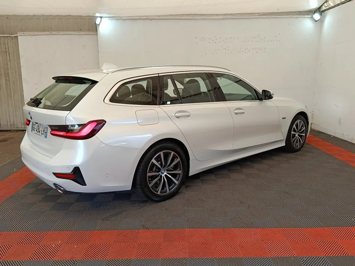 BMW Série 3 320e hybride blanche vue de trois quarts arrière droit, avec feux arrière LED et jantes alliage.