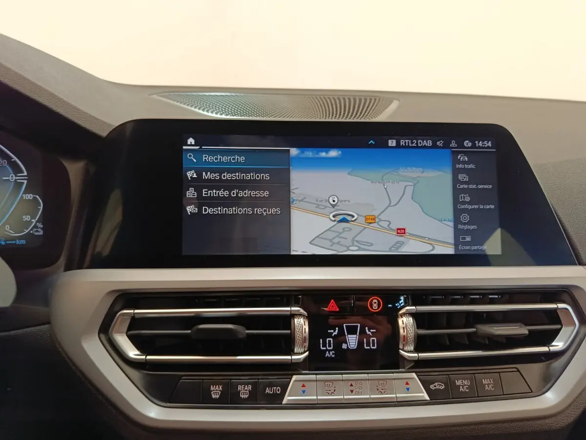 Vue rapprochée de l’écran tactile de navigation 3D et de la console centrale de la BMW Série 3 blanche hybride 320e.