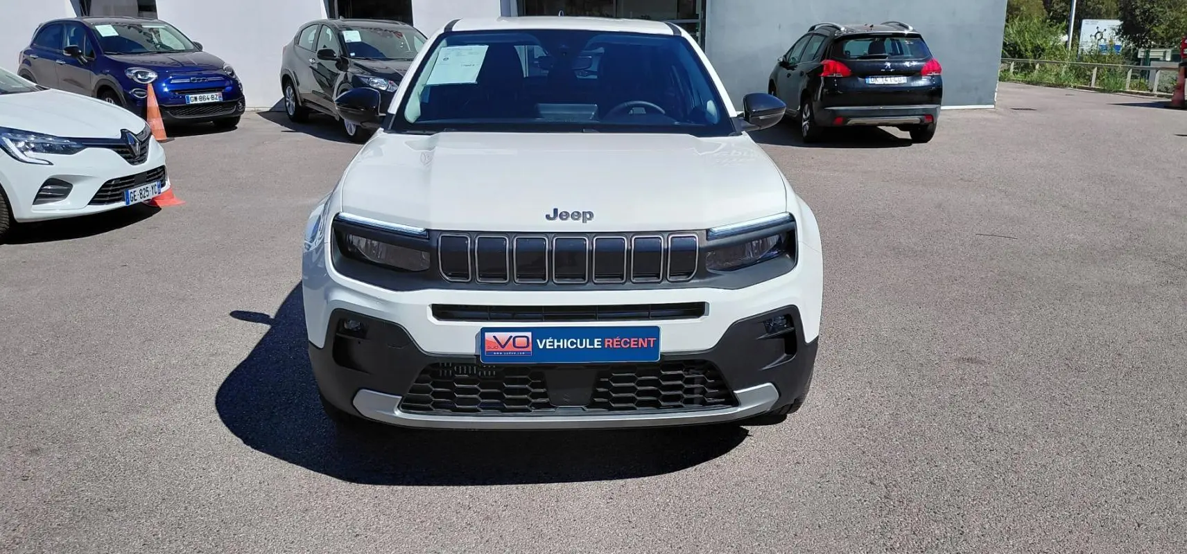 Vue frontale d'un Jeep Avenger blanc 2025 avec calandre noire distinctive et plaque "Véhicule récent".