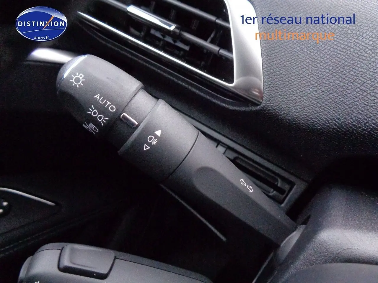 Gros plan sur la commande des phares et clignotants dans l'habitacle noir d'un Peugeot 3008 2023.