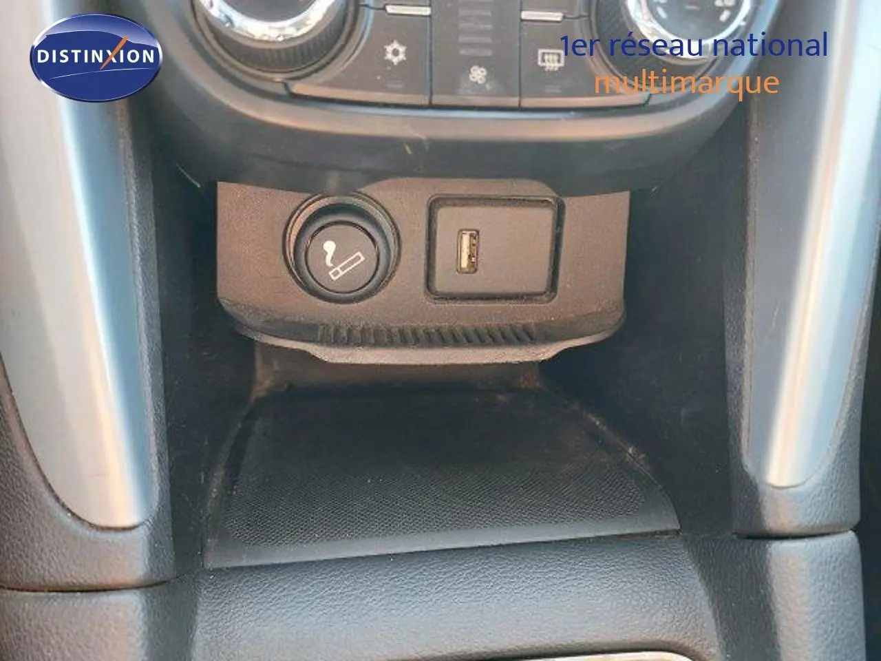 Prise allume-cigare et port USB sur la console centrale de l'Opel Zafira noire métal, vue rapprochée intérieure.