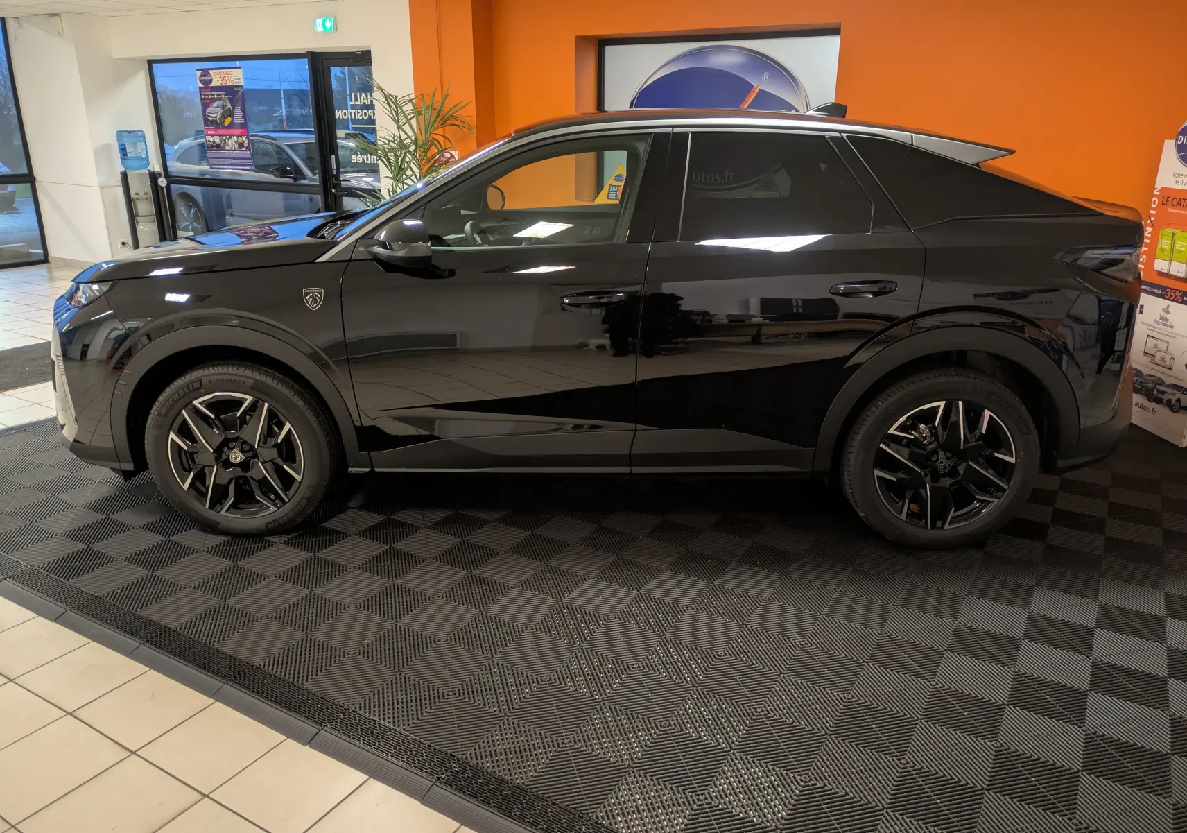 Vue latérale droite d'un Peugeot 3008 Hybrid 145 noir, avec jantes alliage 19'' et vitres arrière surteintées en showroom.