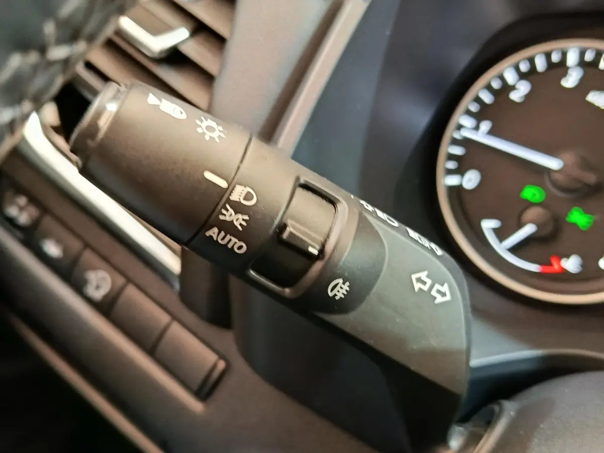 Gros plan sur la manette de clignotants et phares du tableau de bord du Nissan Qashqai gris foncé, 2022.