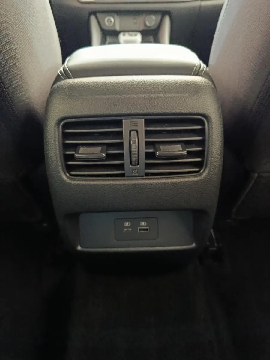Vue rapprochée de la console arrière noire du Nissan Qashqai 2022 avec aérateurs et ports USB visibles.