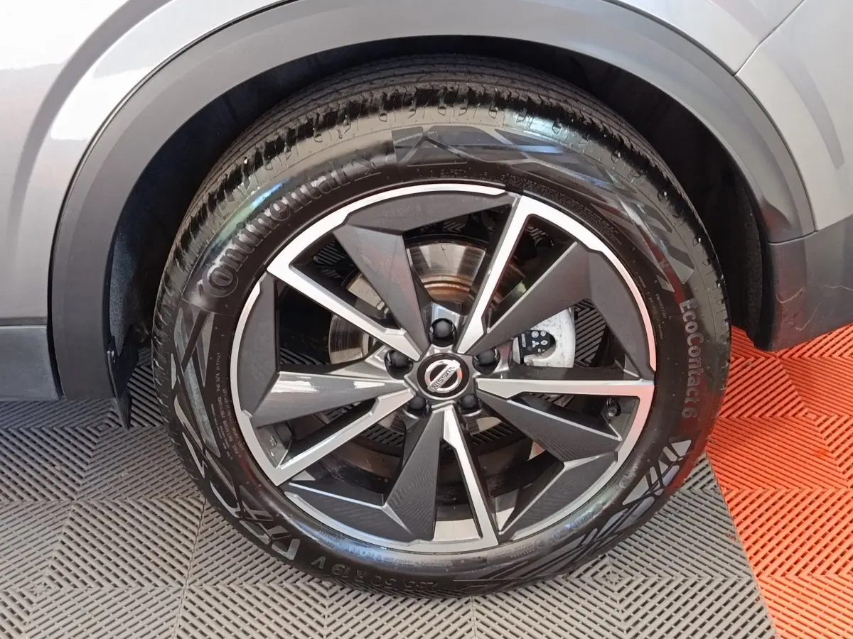 Gros plan sur la roue avant droite du Nissan Qashqai gris foncé, mettant en valeur la jante alliage au design moderne.