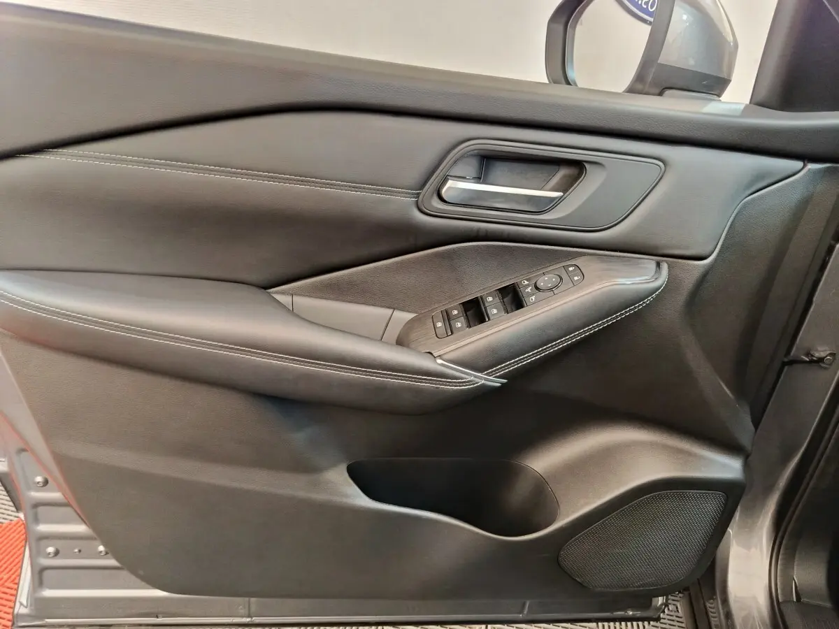 Vue rapprochée de la porte avant gauche du Nissan Qashqai gris foncé avec commandes électriques et garniture cuir.