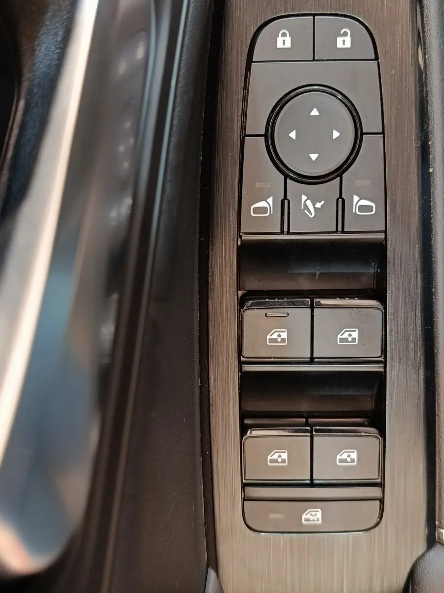 Gros plan sur les commandes de lève-vitres et rétroviseurs côté conducteur du Nissan Qashqai gris foncé 2022.