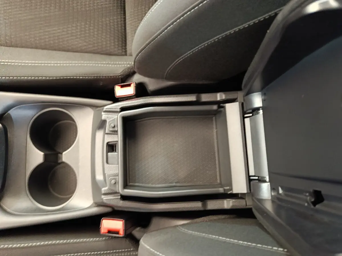 Vue intérieure en plongée du rangement central ouvert entre les sièges avant gris foncé du Nissan Qashqai 2022.