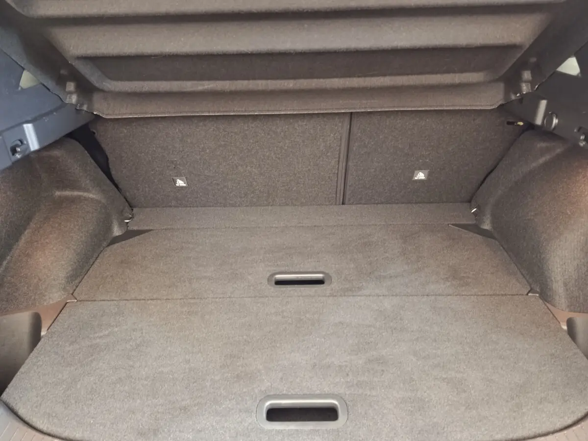 Vue intérieure du coffre gris foncé du Nissan Qashqai 1.3 MHEV 158ch, avec plancher plat et banquette arrière rabattue.