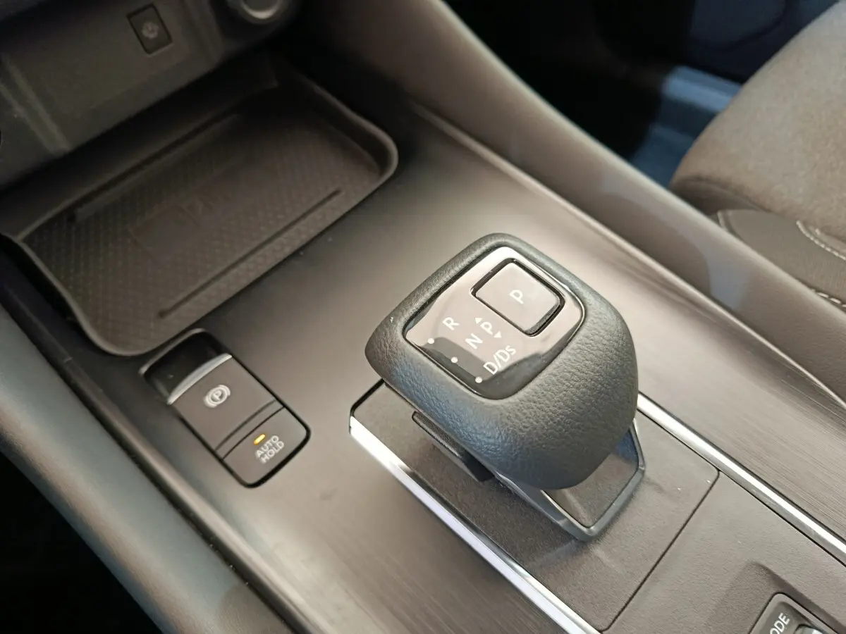 Gros plan sur la commande de boîte automatique noire et le bouton frein à main électrique du Nissan Qashqai gris foncé, intérieur.