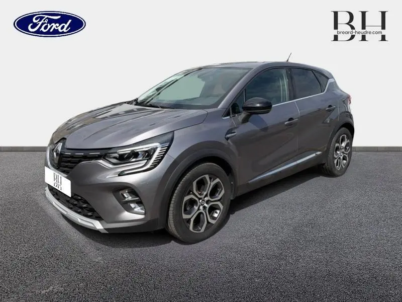 Renault Captur gris Cassiopée en 3/4 avant droit, avec jantes alu et feux LED distinctifs.