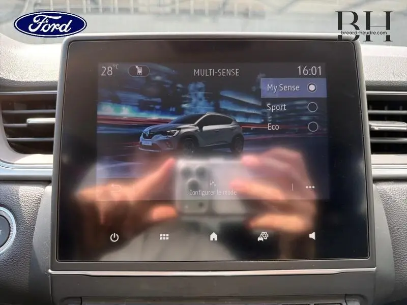 Écran tactile intérieur montrant une Renault Captur gris Cassiopée en vue 3/4 avant avec options de mode de conduite.