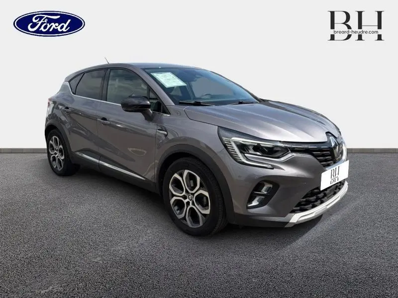 Renault Captur gris Cassiopée en 3/4 avant droit, avec jantes alu et feux LED distinctifs.