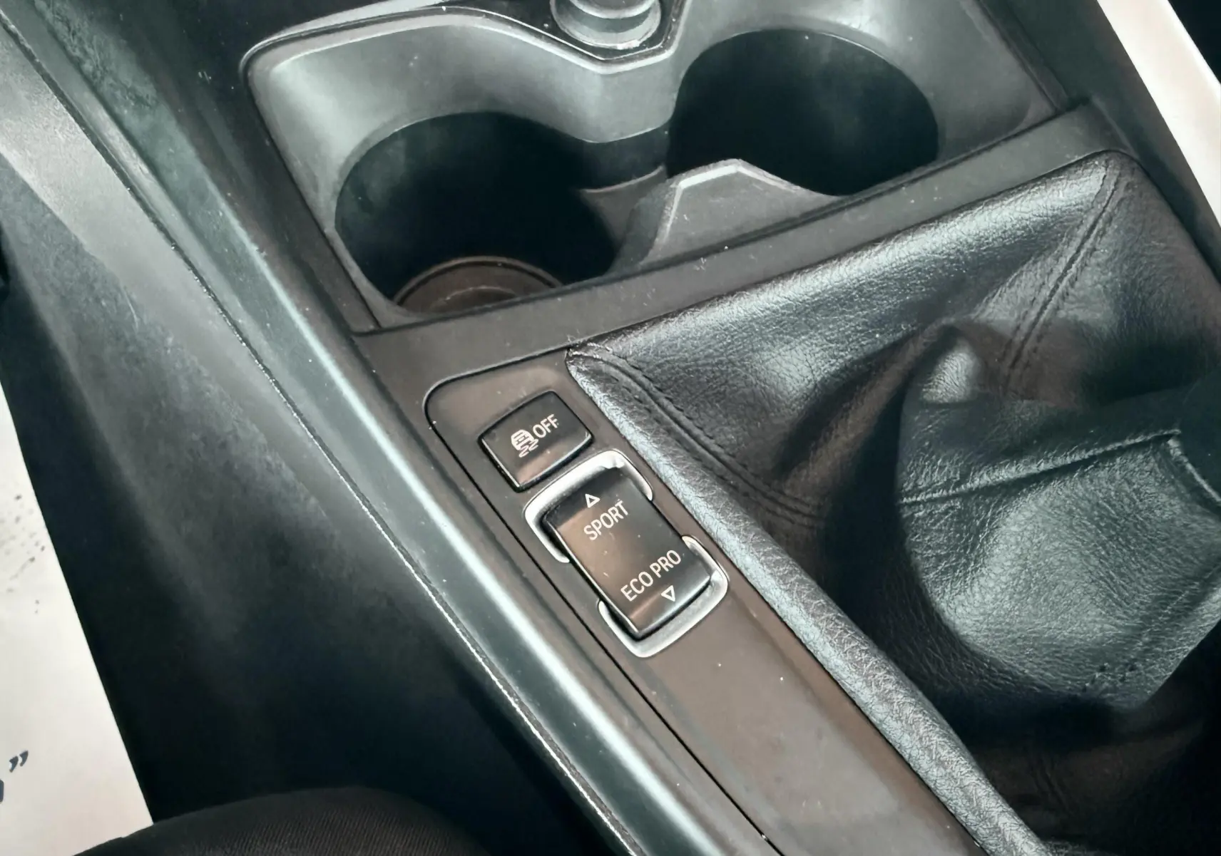 Gros plan sur la console centrale de la BMW Série 1 noire, montrant le levier de vitesses manuel et les boutons modes Sport et Eco Pro.