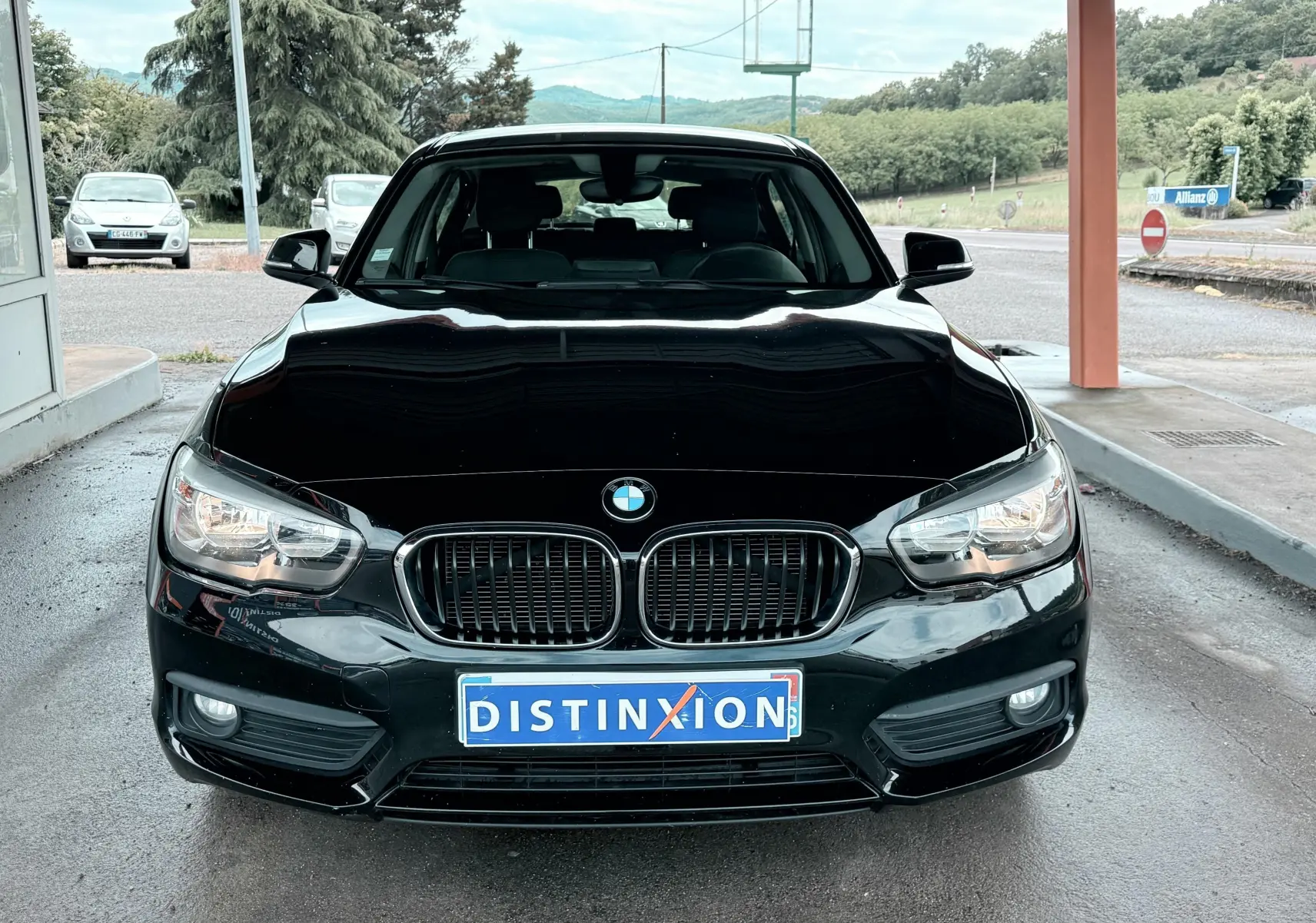 Vue avant d'une BMW Série 1 noire de 2016 avec calandre double haricot et phares allumés sous abri.