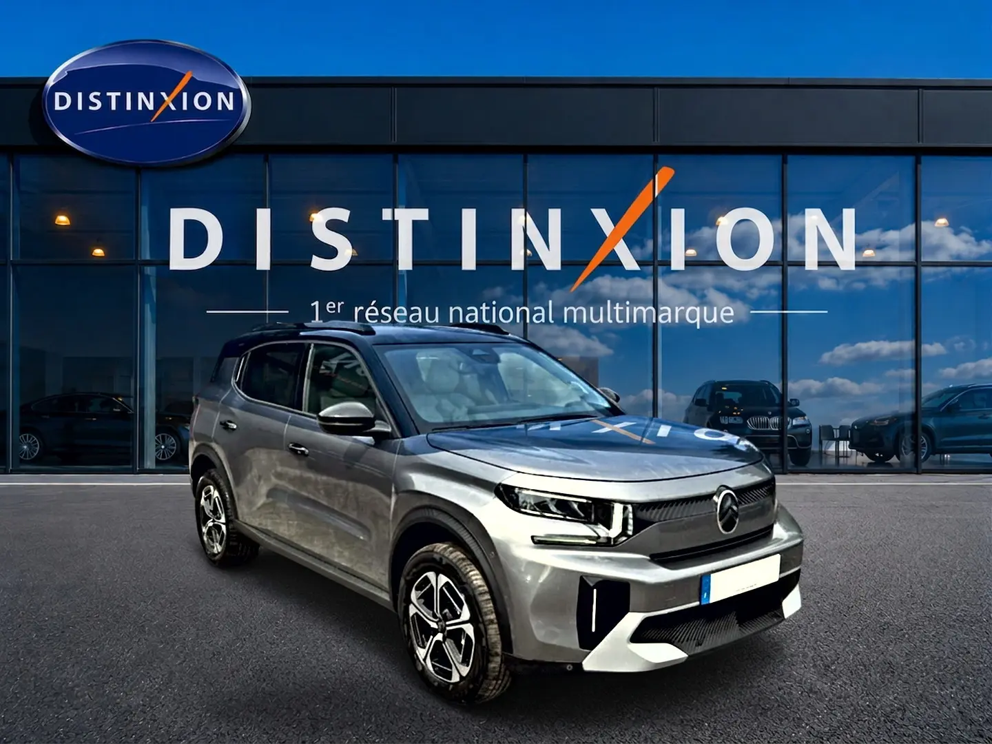 Vue 3/4 avant d'un Citroën C3 Aircross gris mercury avec jantes alu, devant une vitrine Distinxion.