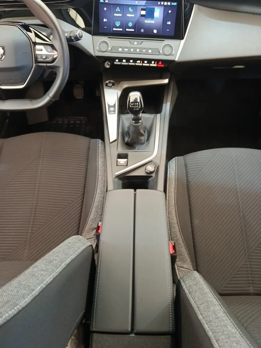 Vue intérieure centrée sur la console centrale et levier de vitesse manuel d'une Peugeot 308 blanche 2024.