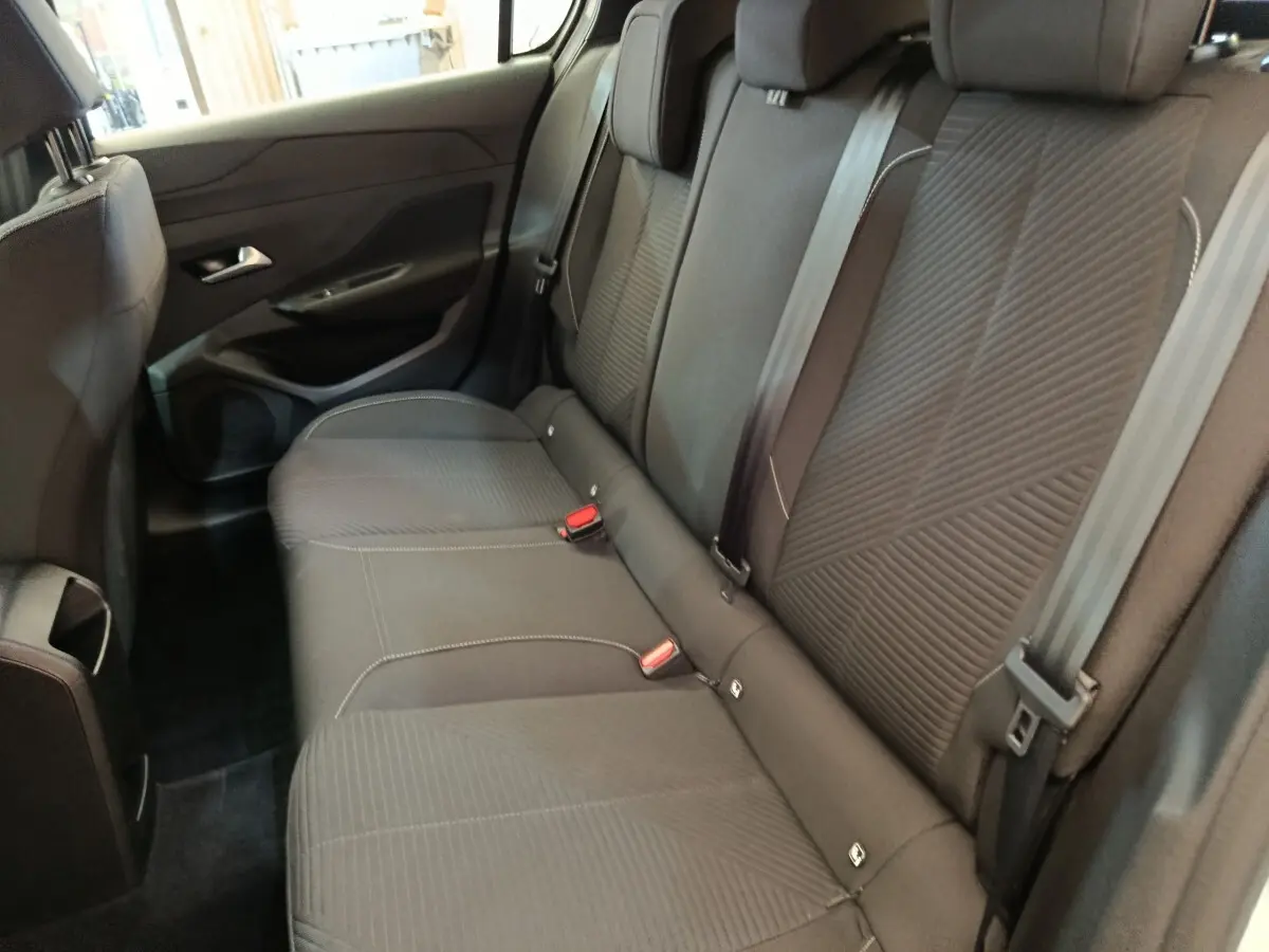 Vue intérieure montrant la banquette arrière noire de la Peugeot 308 2024, avec ceintures et appuie-têtes visibles.