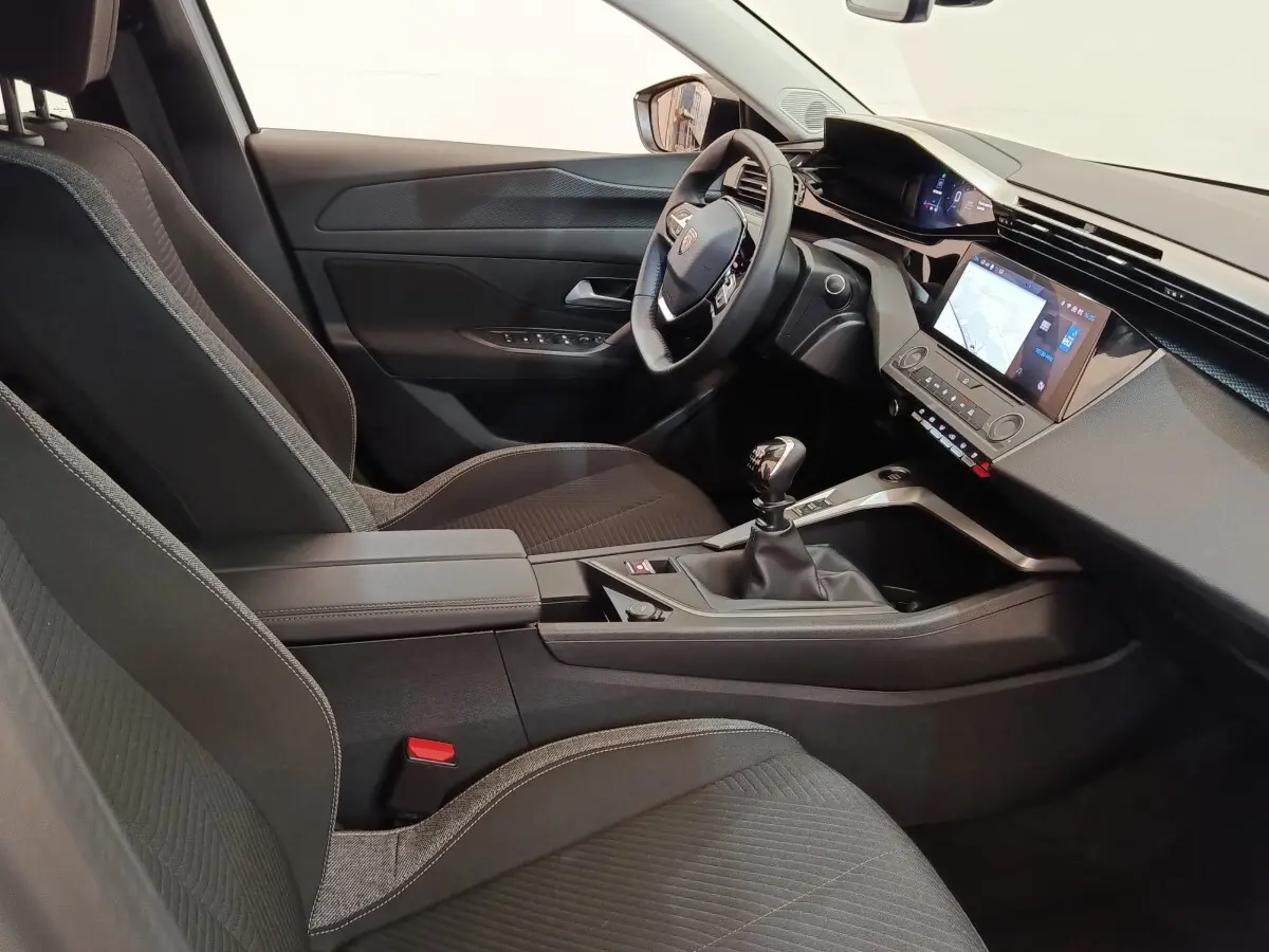 Intérieur de la Peugeot 308 2024 vue côté conducteur, sièges noirs, tableau de bord avec écran tactile et volant cuir.