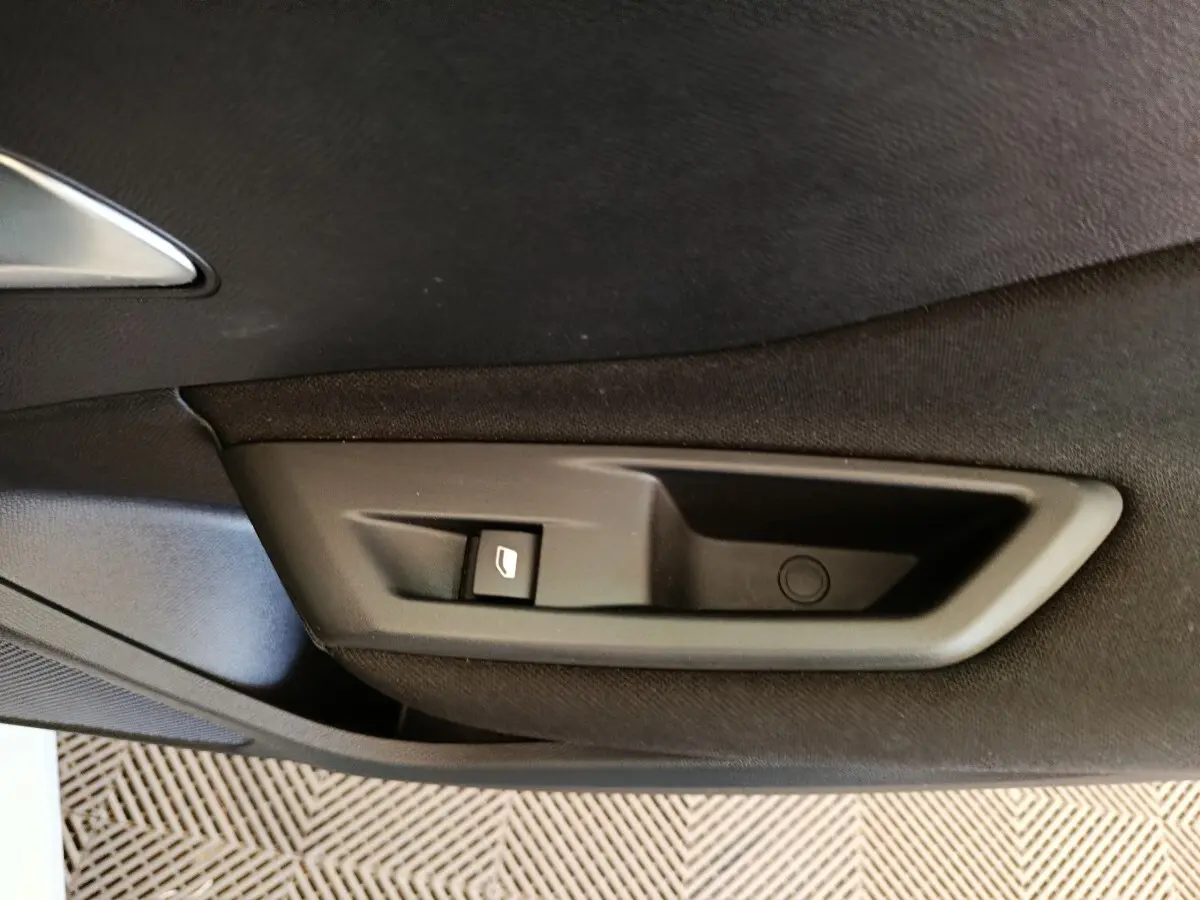 Gros plan sur la commande de lève-vitre côté intérieur d'une porte noire d'une Peugeot 308 blanche 2024.