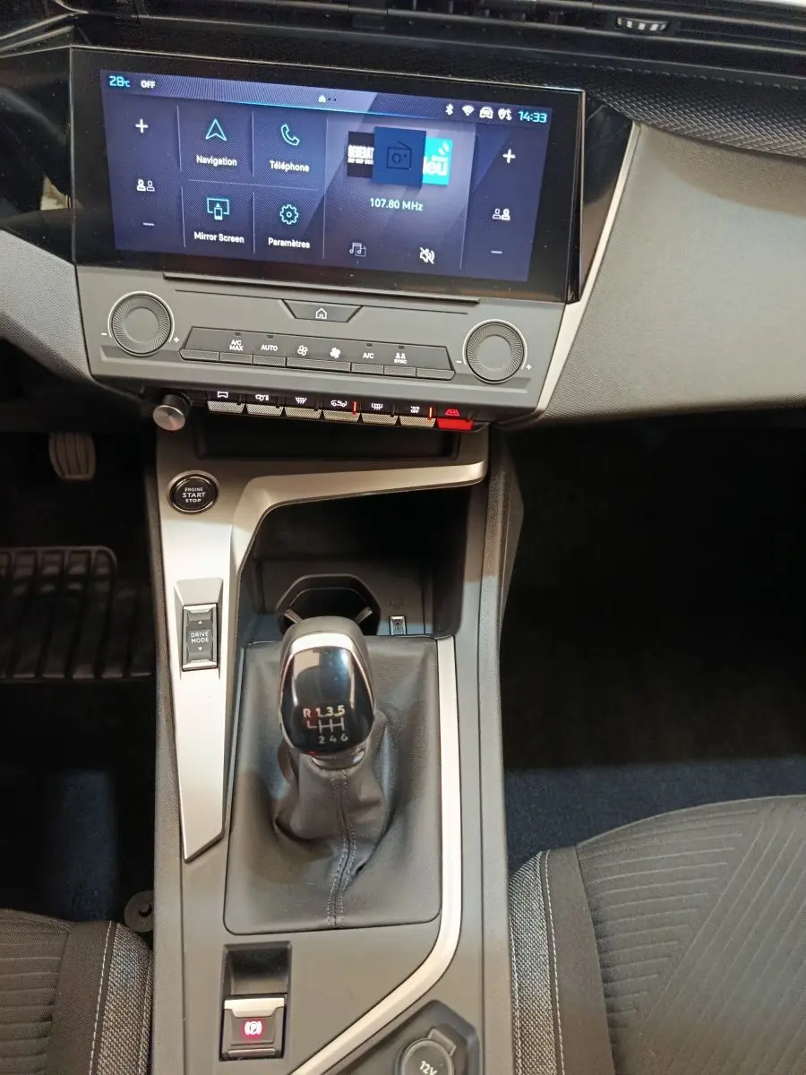 Vue intérieure centrée sur la console centrale de la Peugeot 308 blanche 2024 avec boîte manuelle et écran tactile 10 pouces.