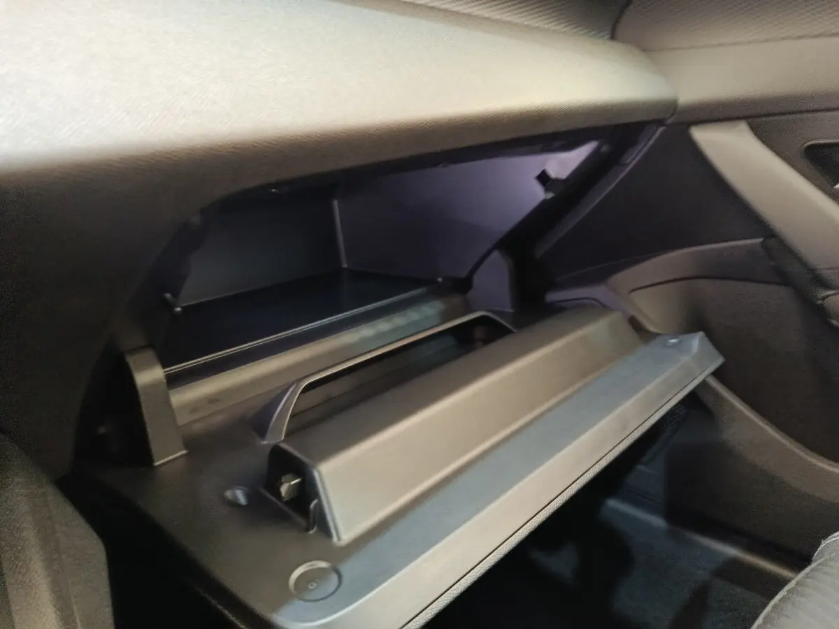 Gant de rangement ouvert côté passager dans l'habitacle sombre d'une Peugeot 308 blanche 2024.
