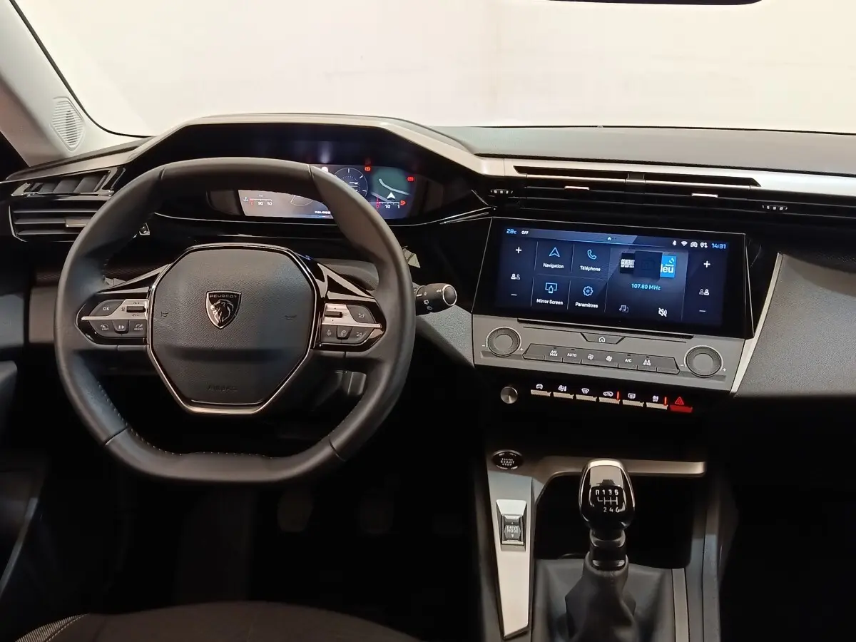Vue intérieure centrée sur le volant cuir multifonctions et la console avec écran tactile de la Peugeot 308 2024.