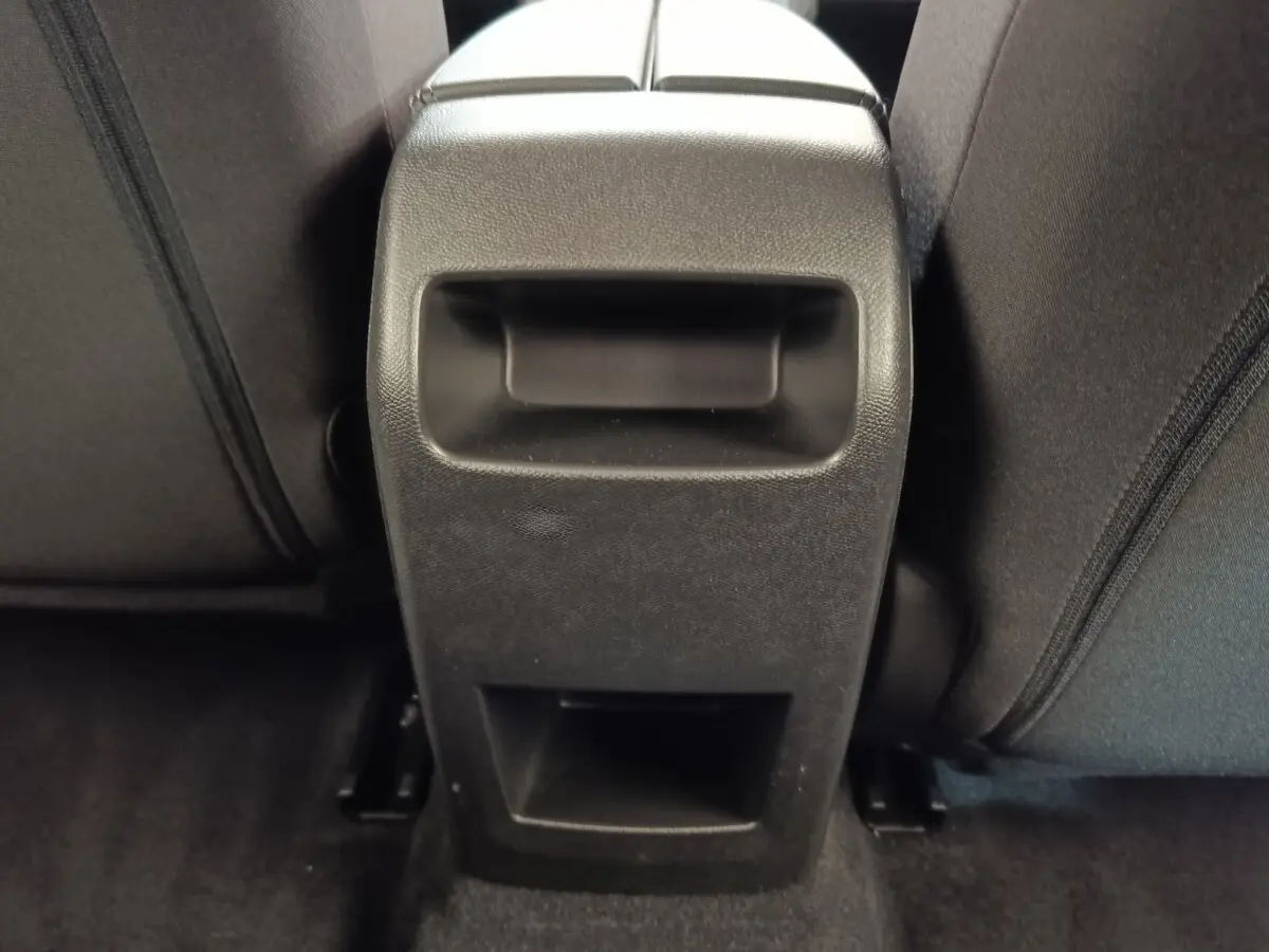 Détail de la console centrale arrière noire entre les sièges arrière d'une Peugeot 308 blanche 2024.