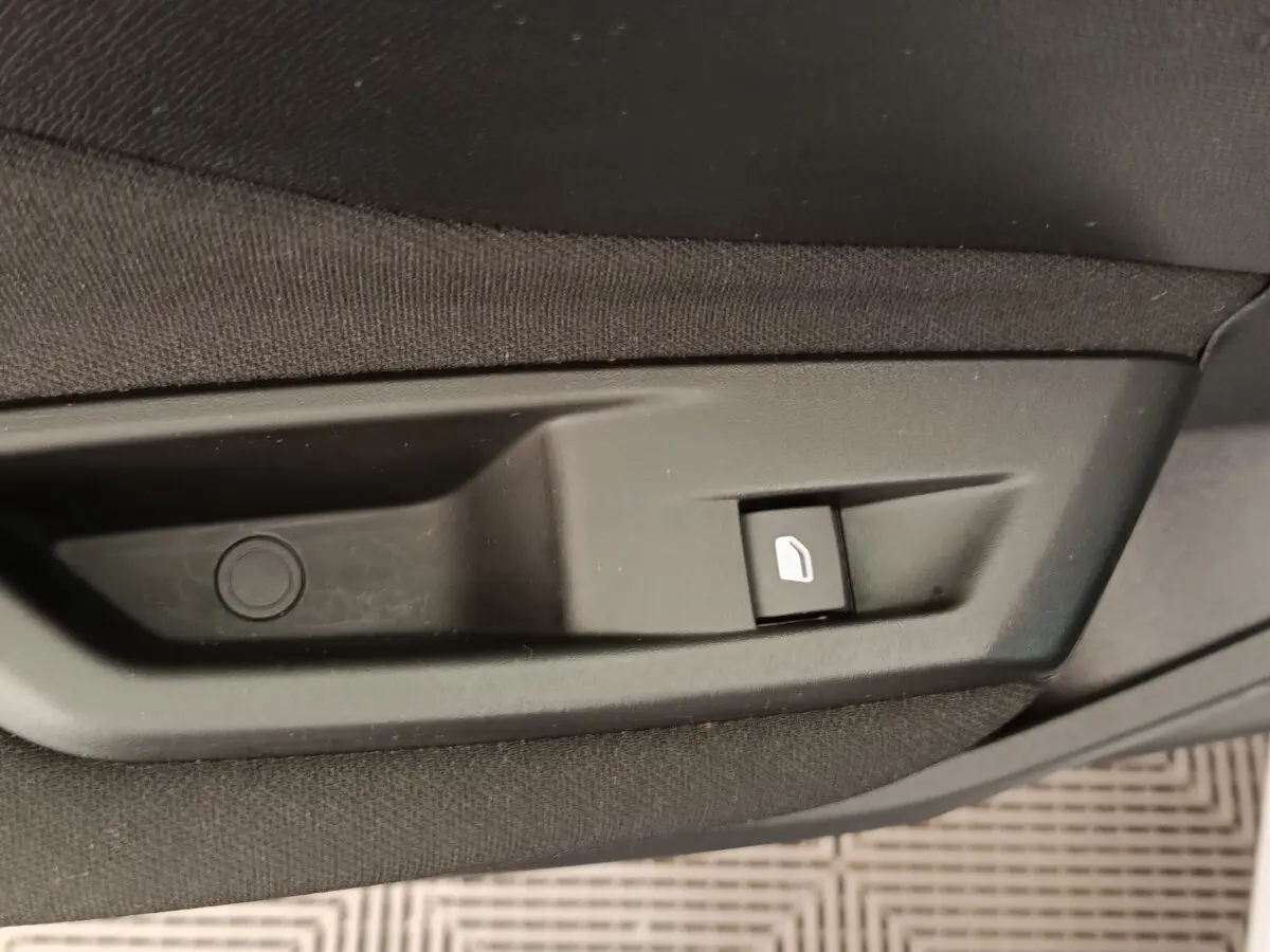 Bouton de commande de lève-vitre électrique côté porte intérieure d'une Peugeot 308 blanche 2024.
