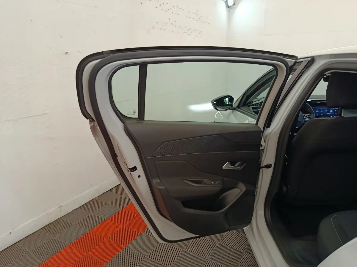 Vue intérieure côté gauche de la porte arrière ouverte d'une Peugeot 308 blanche, avec sellerie noire visible.
