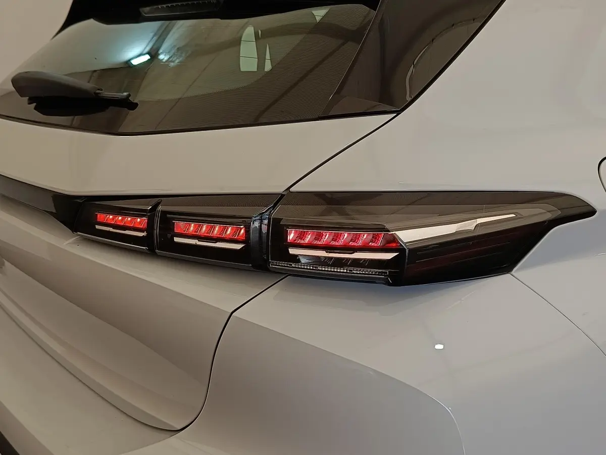 Gros plan sur le feu arrière droit rouge et noir d'une Peugeot 308 blanche, version 2024, vue de l'arrière côté droit.