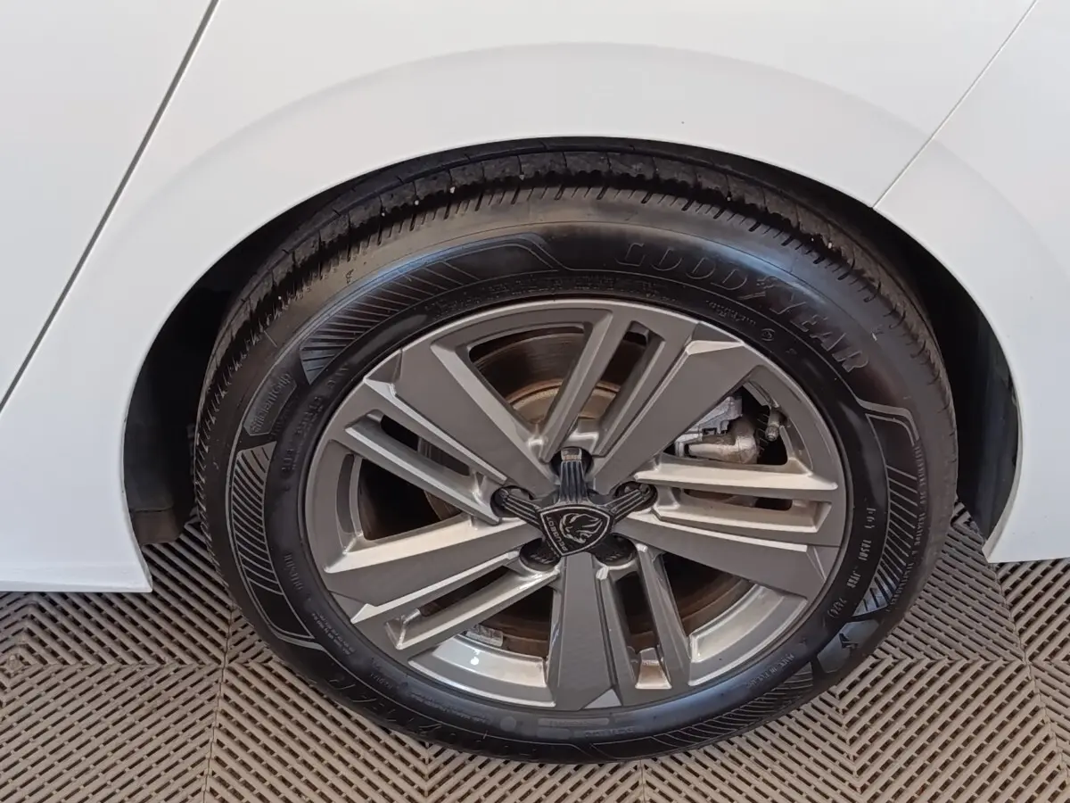 Gros plan sur la roue arrière droite d’une Peugeot 308 blanche avec jante alliage et pneu Goodyear.