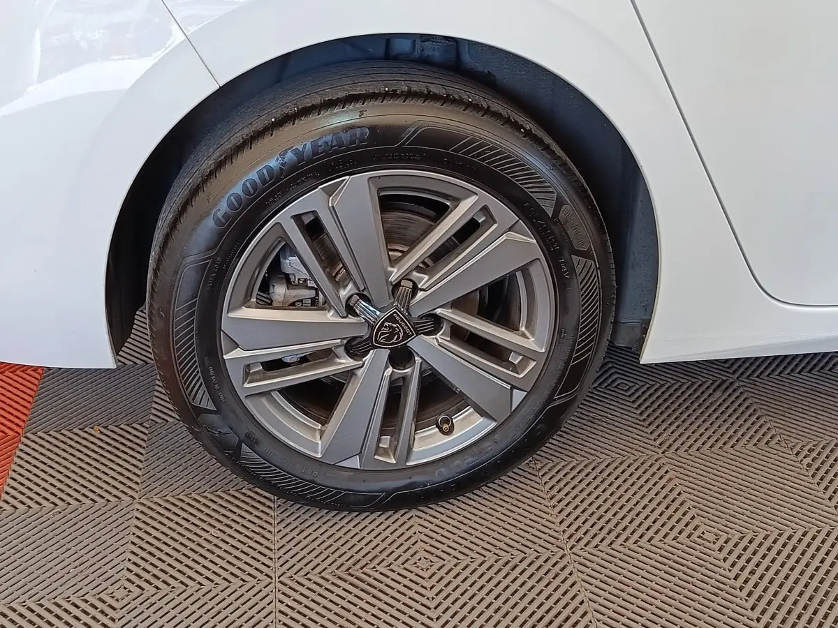 Gros plan sur la roue arrière droite d'une Peugeot 308 blanche avec jante alliage et pneu Goodyear.