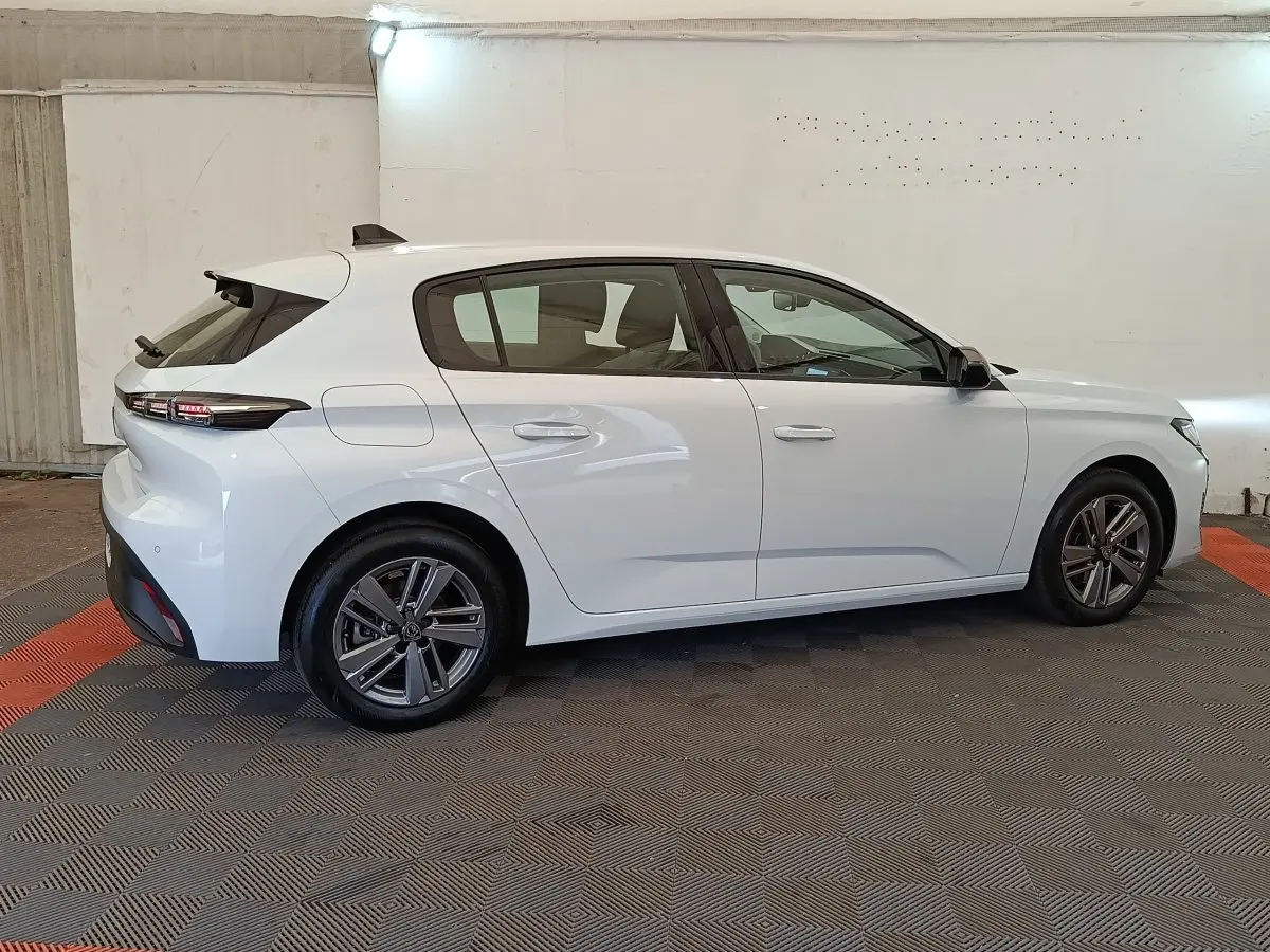 Peugeot 308 blanche vue de profil côté gauche dans un garage, avec feux arrière LED et jantes alliage.
