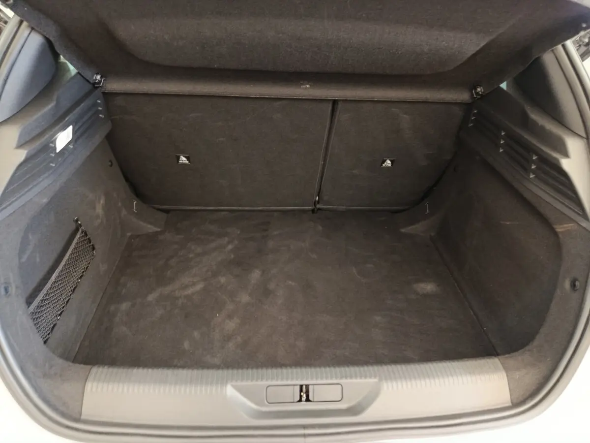 Coffre ouvert de Peugeot 308 blanc, vue intérieure montrant l'espace de chargement et la banquette arrière rabattable.