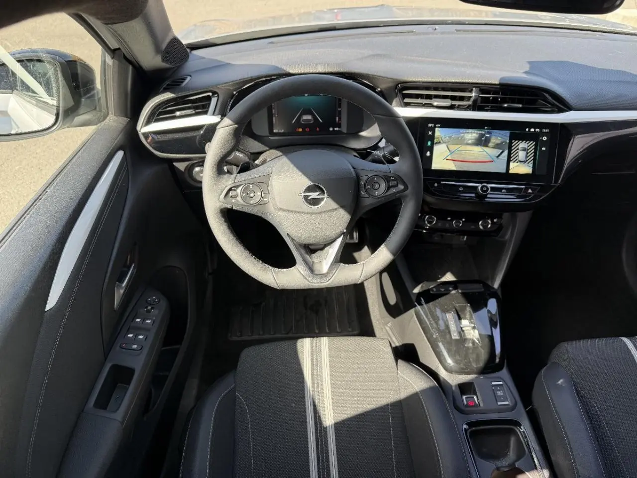 Vue intérieure frontale du poste de conduite de l’Opel Corsa 1,2 Hybrid 2025 avec volant multifonction et écran tactile.