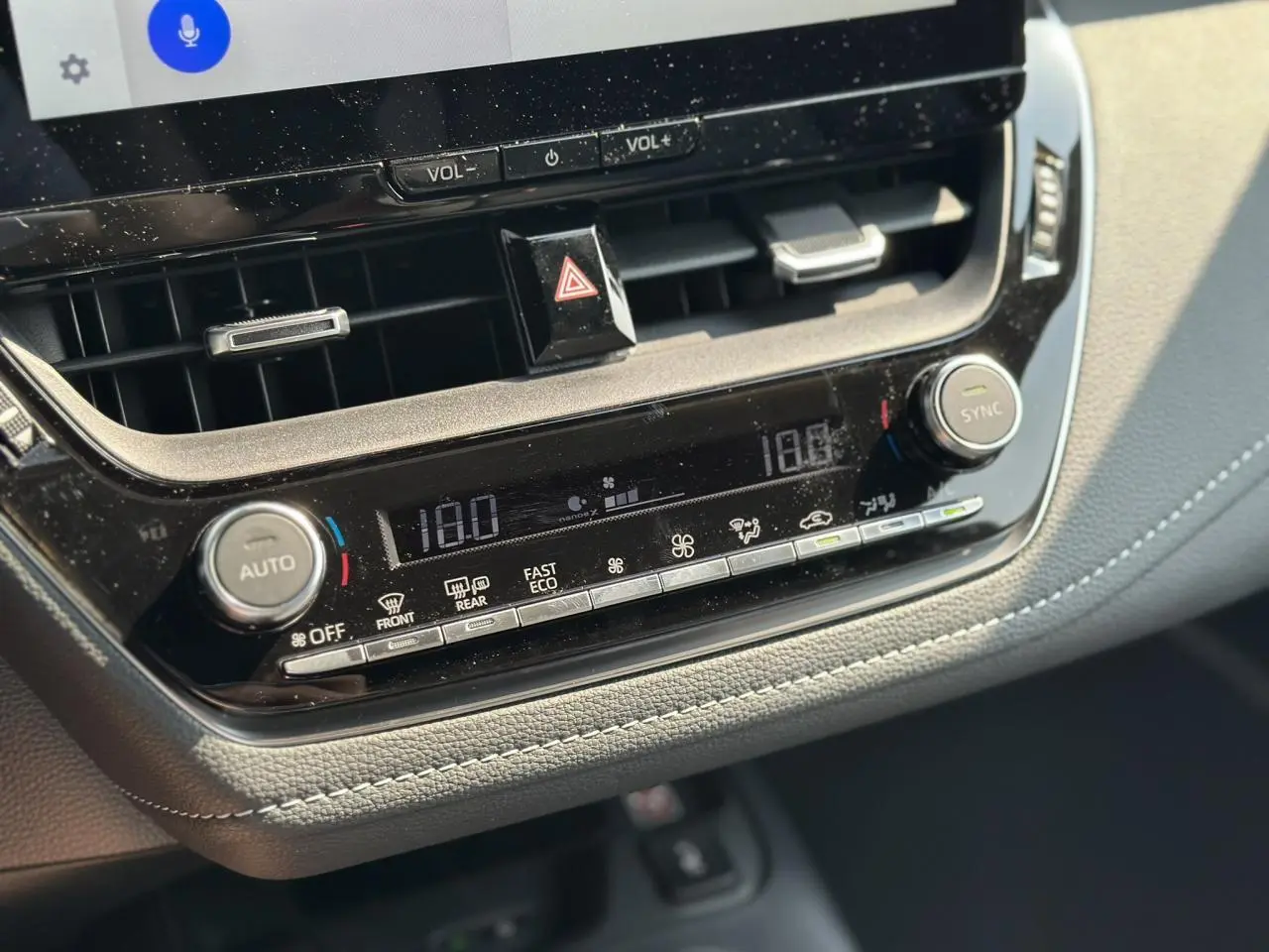 Détail de la console centrale avec climatisation automatique bi-zone et commandes digitales dans la Toyota Corolla Touring Sport blanche.