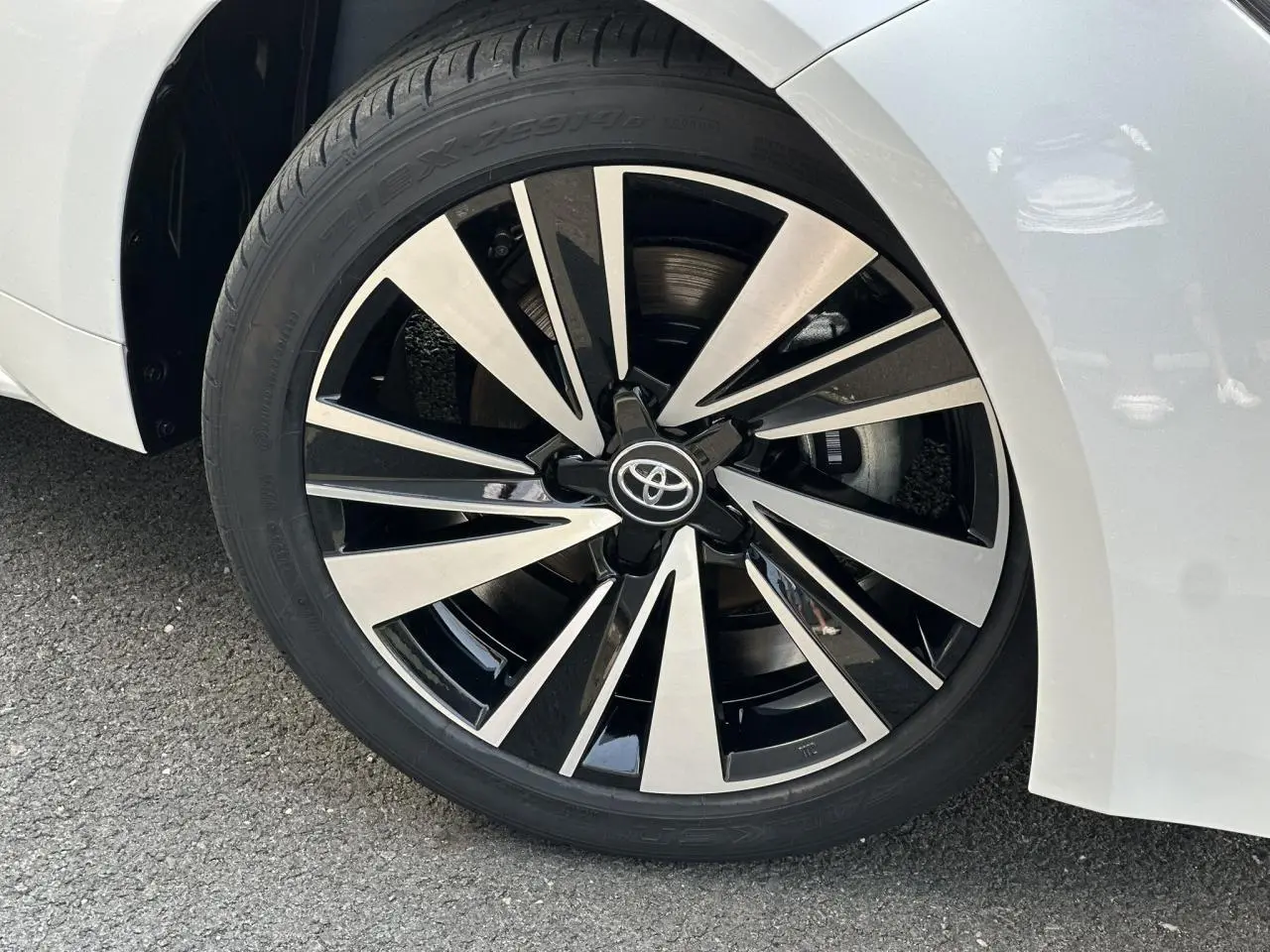 Gros plan sur la jante alliage 17'' diamantée grise et noire de la Toyota Corolla Touring Sport blanc neige, côté avant droit.