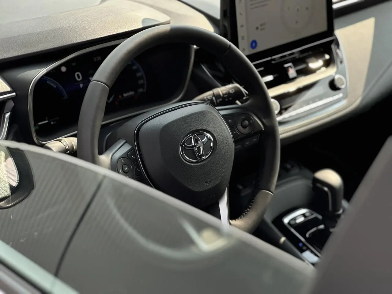 Vue rapprochée du volant multifonction noir et du tableau de bord numérique de la Toyota Corolla Touring Sport 2025.