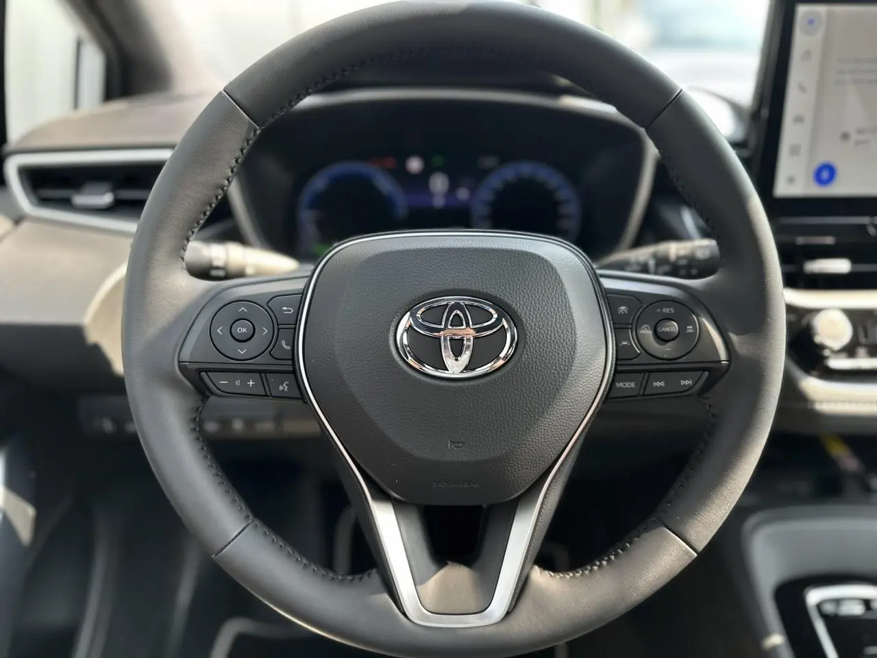 Volant multifonction en cuir noir avec logo Toyota au centre dans l'habitacle de la Corolla Touring Sport 2025.