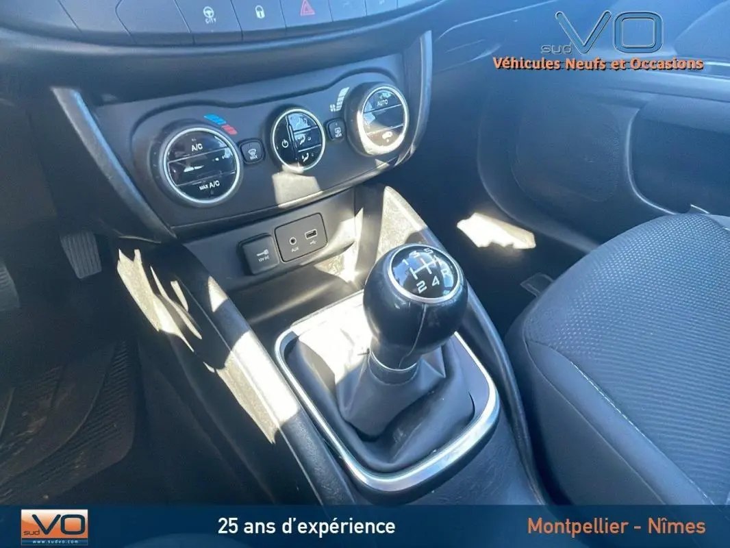 Gros plan sur la console centrale et levier de vitesses manuel d'une Fiat Tipo gris, avec commandes climatisation visibles.