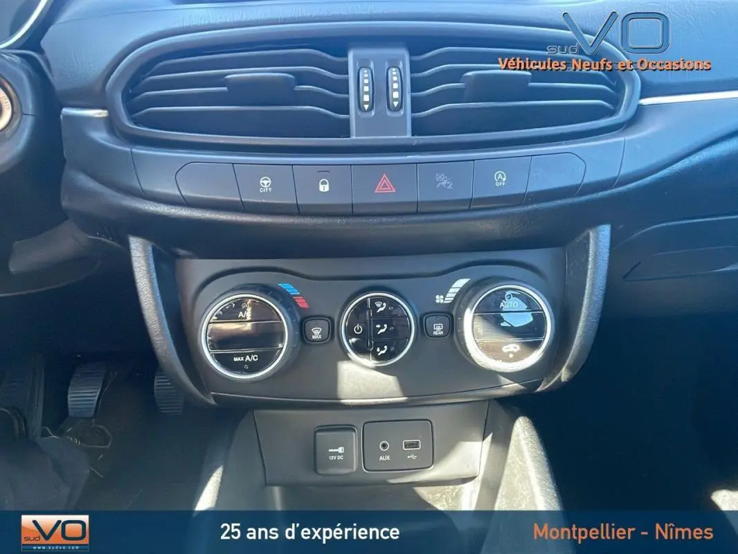 Tableau de bord de Fiat Tipo gris, vue rapprochée sur commandes climatisation et prises 12V, USB, AUX.