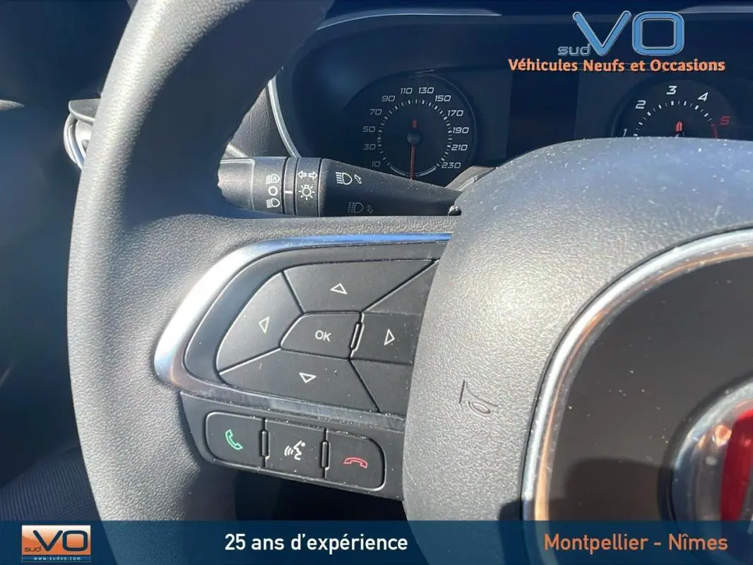 Gros plan sur le volant multifonction noir du Fiat Tipo Station Wagon gris, avec commandes audio et téléphone intégrées.